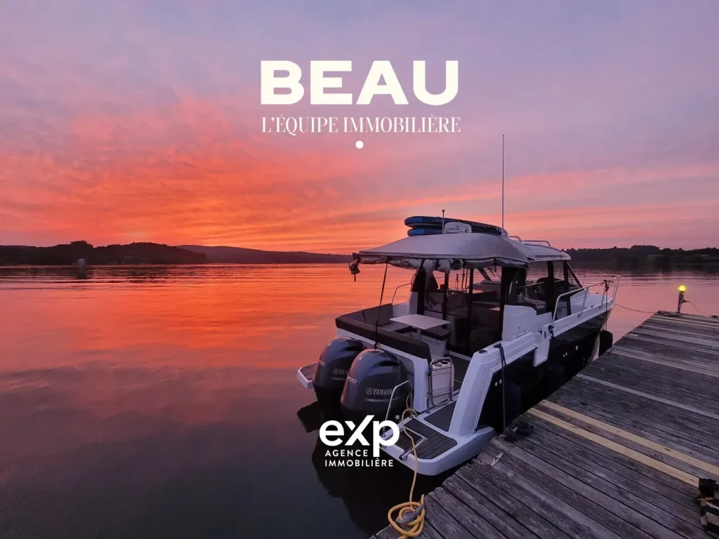 Le bateau BEAU au quai au coucher du soleil, avec les logos de BEAU L’Équipe immobilière et d’eXp Agence immobilière